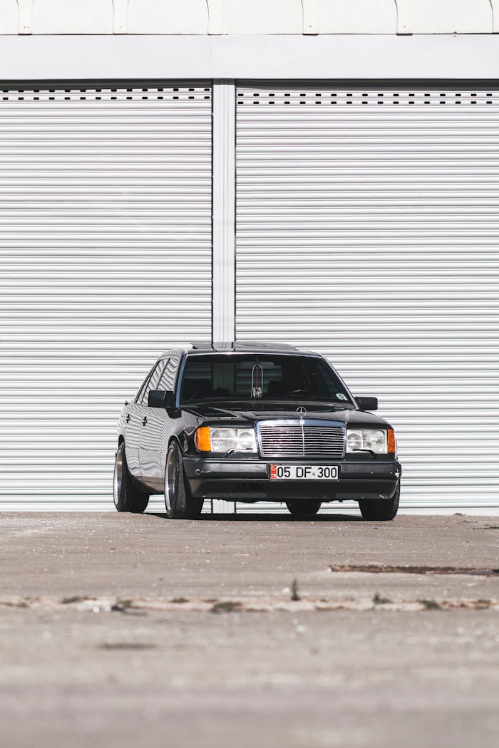 services-03 Elegant black Mercedes Benz car parked in front of a large garage with white shutters.