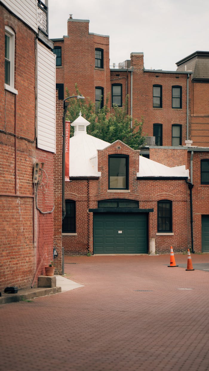 services-01 Photograph of urban red brick buildings with a green garage door and traffic cones in a quiet alleyway.